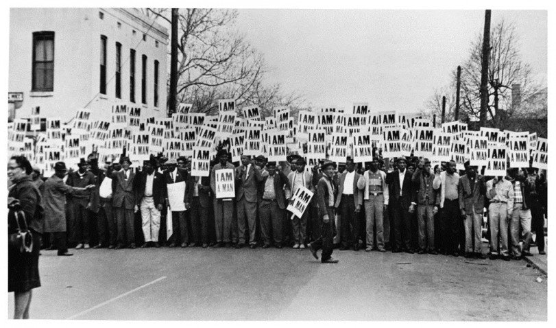 Ernest C. Withers, fotografia strajkujących pracowników oczyszczania miasta w Memphis, Tennessee, 1968, dzięki uprzejmości Ernest C. Withers Estate. W 1968 roku strajkujący robotnicy trzymali  te plakaty aby zaprotestować przeciwko rasistowskiej dyskryminacji w swoim zakładzie pracy. Wydrukowane w kościele, który stał się ich siedzibą, stworzyli jeden z ikonicznych plakatów XX wieku.